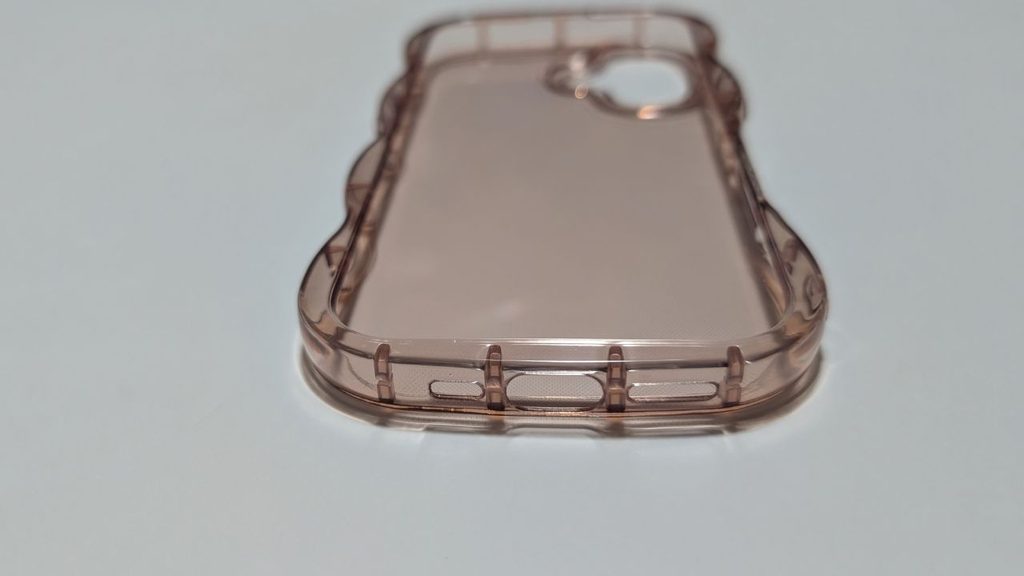 淡いピンク系の透明スマホケースを低い位置から見た写真で、下部や側面など手が触れやすい部分の形状が分かる