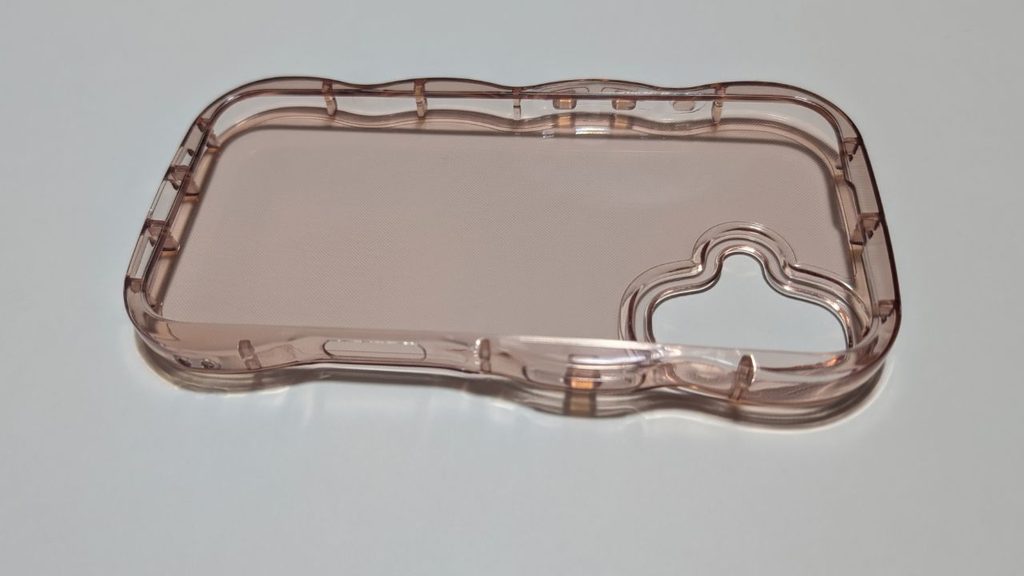 淡いピンク系の透明スマホケースを内側が見えるように斜めから撮影した様子。側面の凹凸やカメラ部分の大きな開口部が見える